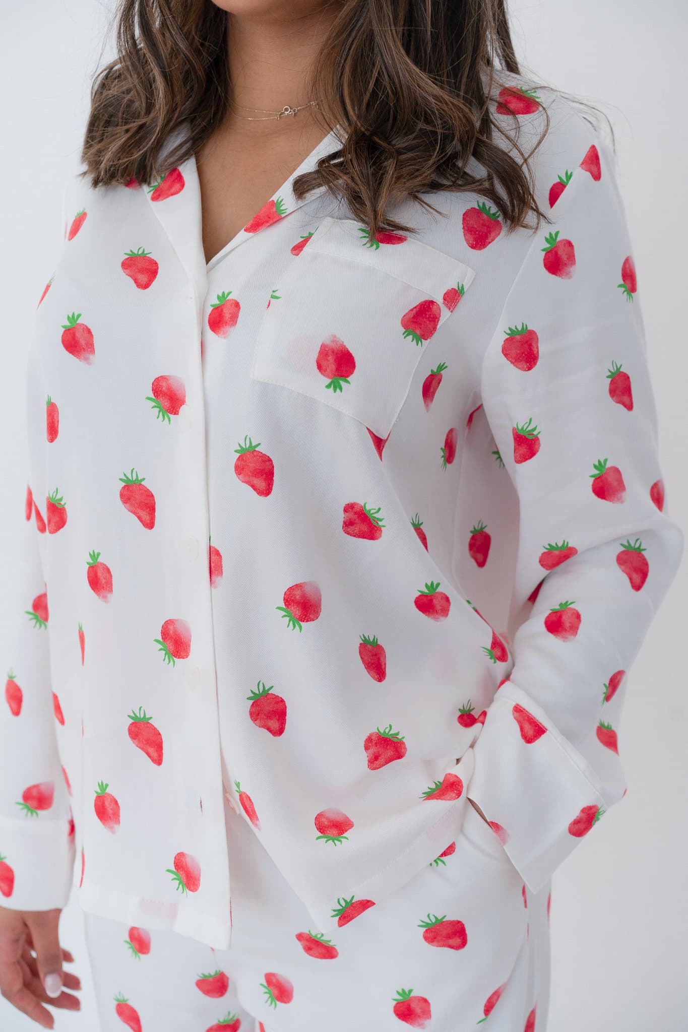 Close up photo of a long sleeve white pyjama top with a strawberry pattern